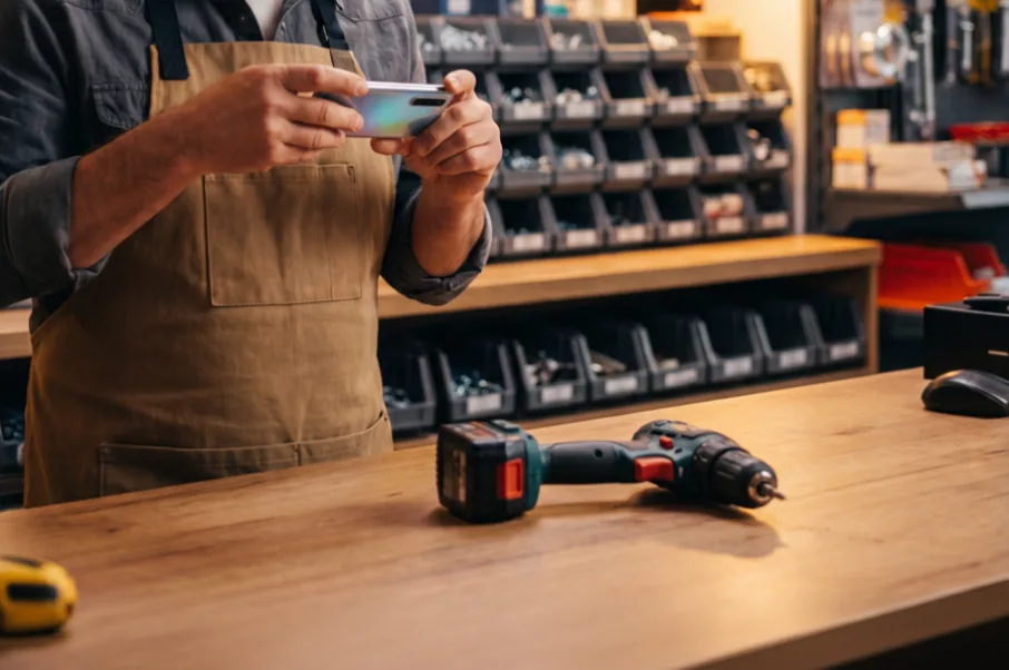 Comerciante sacando una foto a un taladro con el celular para identificarlo en el inventario